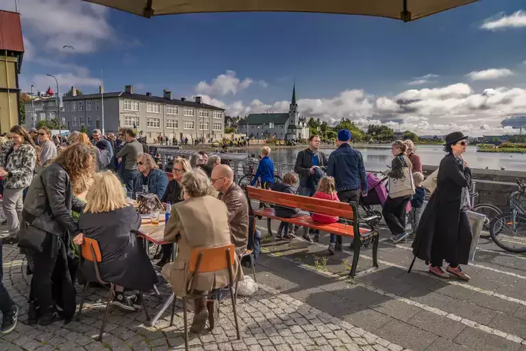 People sitting outside Iðnó on a sunny