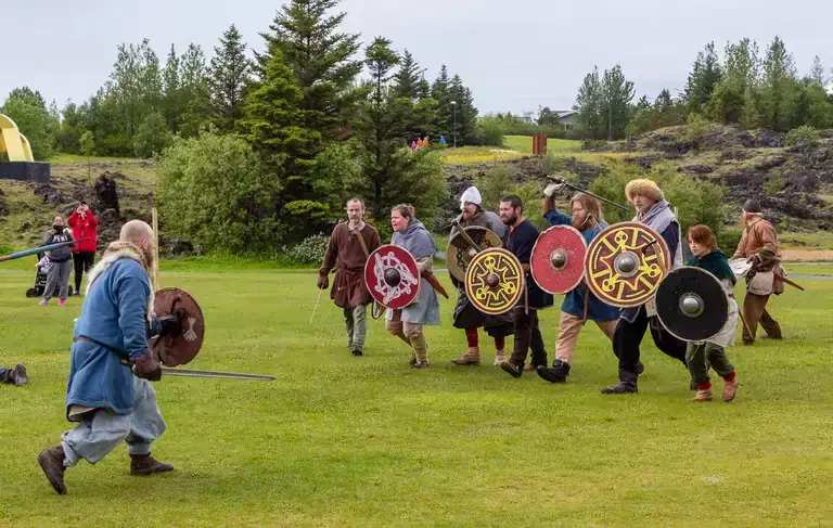 People in viking costumes fake battling