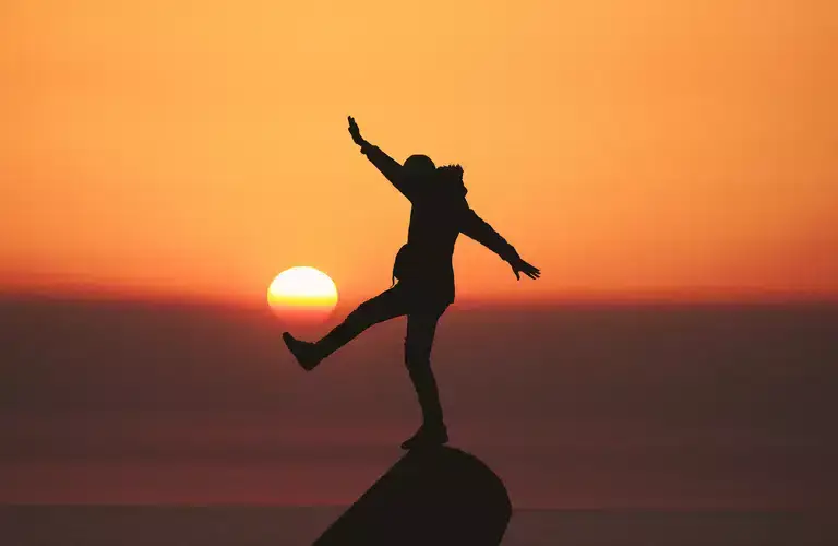 Person standing on a rock during sundown